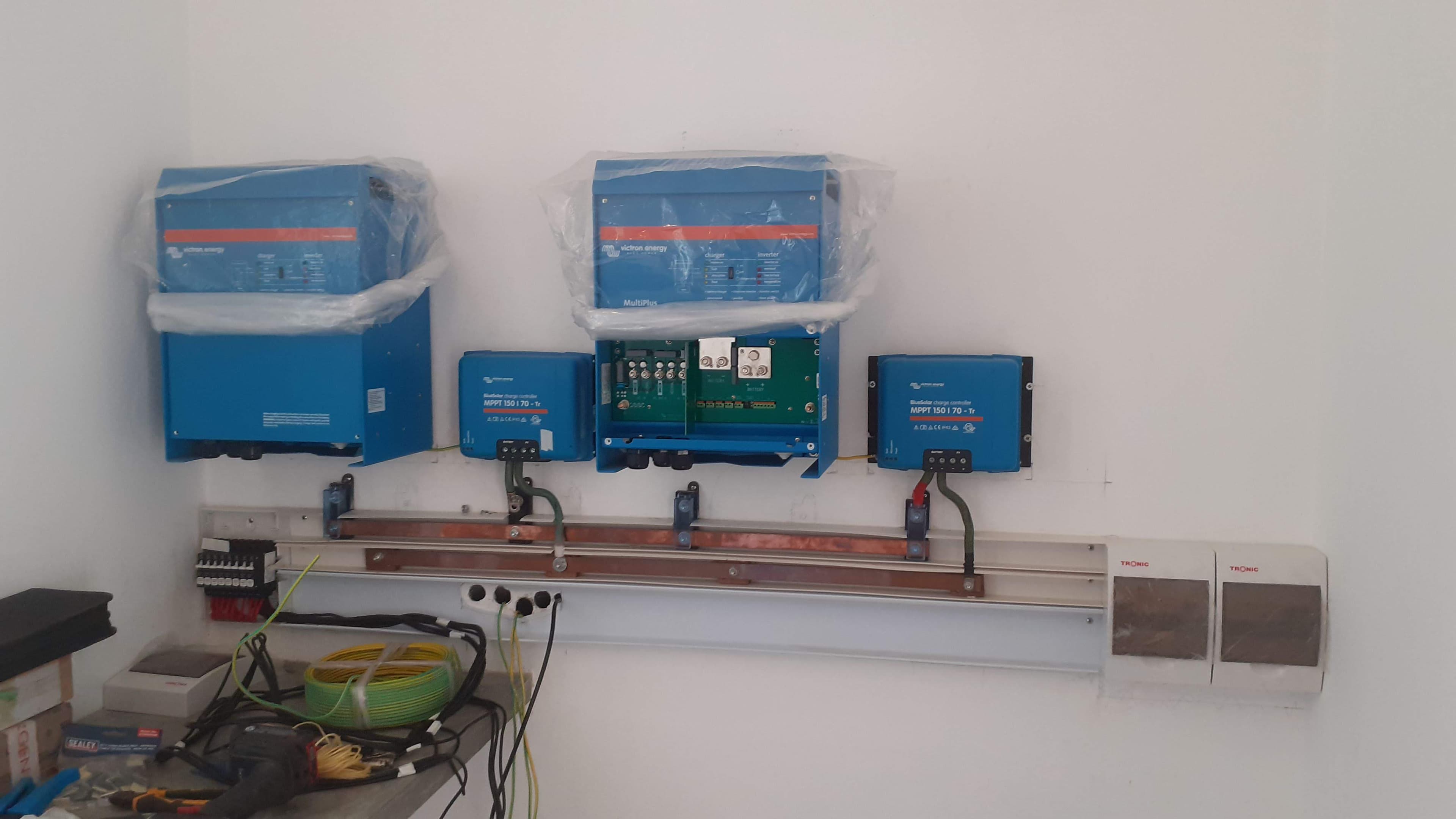 Wall-mounted Victron inverters and charge controllers wired to a copper busbar